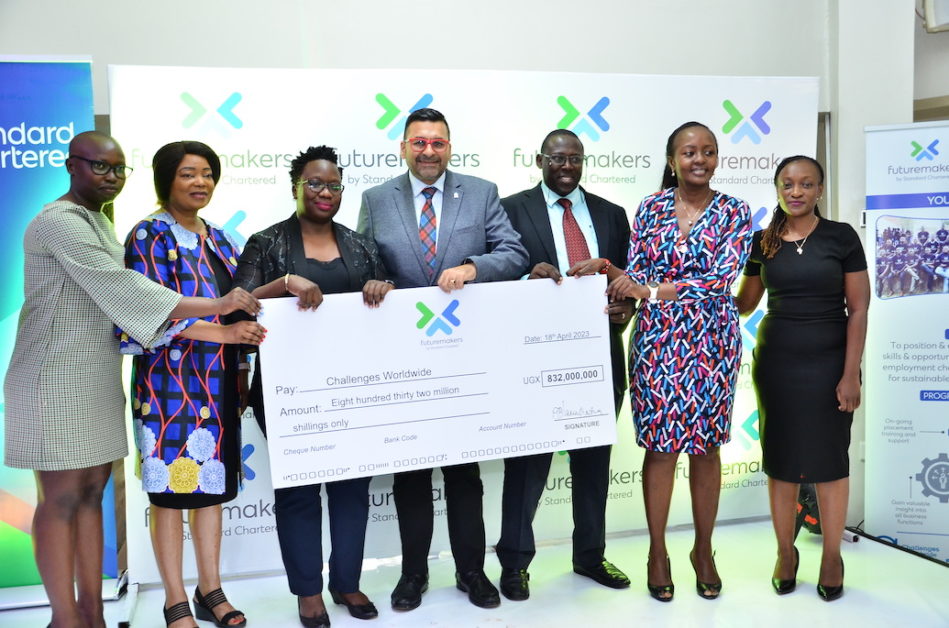 L – R: Peace Amaro (Programmes Lead - Challenges Uganda), Dr. Paulina Chiwangu (UN Women Representative in Uganda), Ms. Hendricah Nabukwasi (Country Lead - Challenges Uganda), Sanjay Rughani (Chief Executive Officer - Standard Chartered Bank), Dr. Joshua Mutambi (Commissioner for Micro, Small & Medium Enterprises at the Ministry of Trade, Industry and Cooperatives), Ms. Joyce Kibe (Head, Corporate Affairs, Brand & Marketing East Africa - Standard Chartered Bank) & Ms. Margaret Kigozi Namulindwa (Head, Corporate Affairs, Brand & Marketing Uganda - Standard Chartered Bank) during the cheque handover at the event.